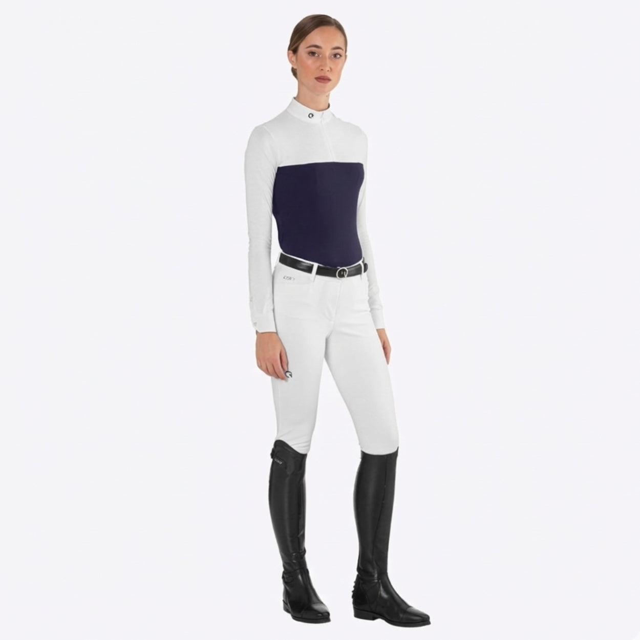 Woman wearing navy and white long sleeve riding shirt, white breeches, black belt, and tall black riding boots